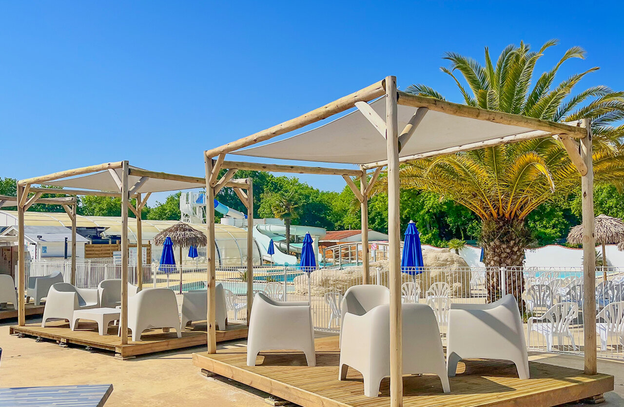 Zona de relax sombreada, piscina, toboganes en el camping VAGUES OCEANES Domaine les Charmilles en Saint-Laurent-de-la-Pr�e (17).