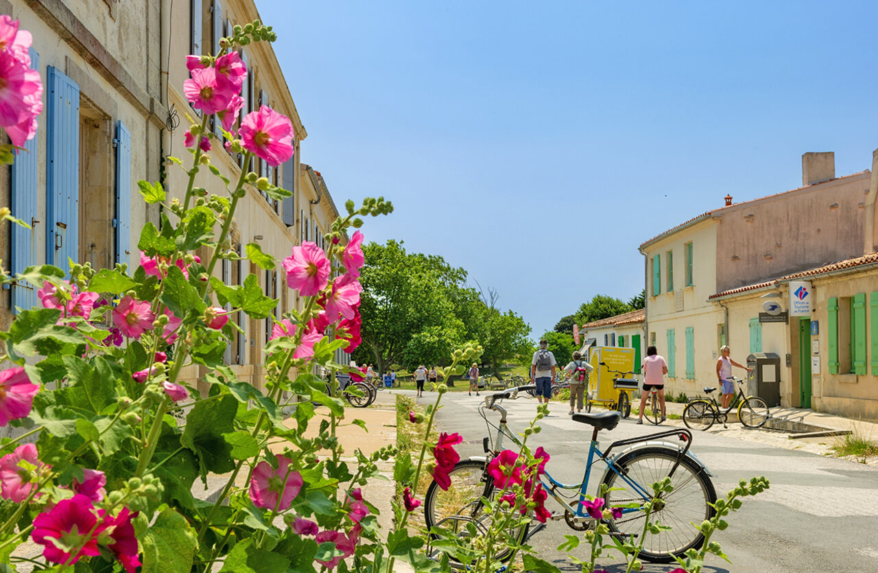 Calle de pueblo florida con bicicletas en el camping VAGUES OCEANES Domaine les Charmilles en Saint-Laurent-de-la-Pr�e (17).