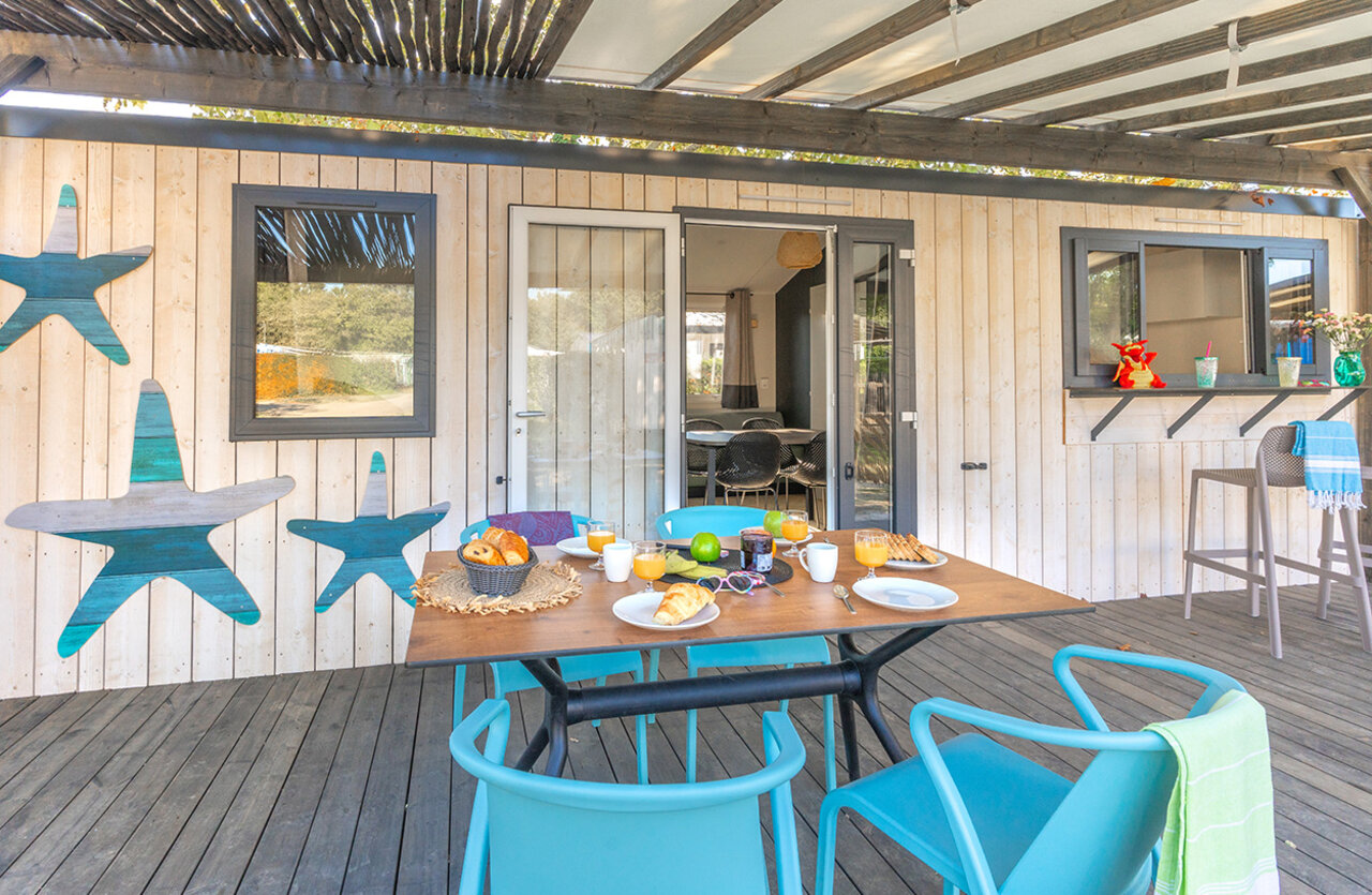 Desayuno en terraza cubierta de mobil-home moderno en el camping VAGUES OCEANES Domaine les Charmilles en Saint-Laurent-de-la-Pr�e (17).