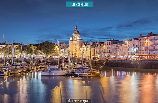 Puerto Viejo de La Rochelle iluminado con la Torre del Reloj y barcos.