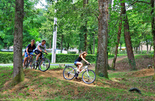 J�venes en bicicleta por sendero arbolado en camping VAGUES OCEANES Chataigneraie.