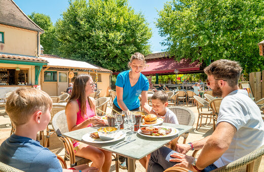 Familia almorzando en la terraza del restaurante en el camping VAGUES OCEANES Chataigneraie en Prats-de-Carlux.