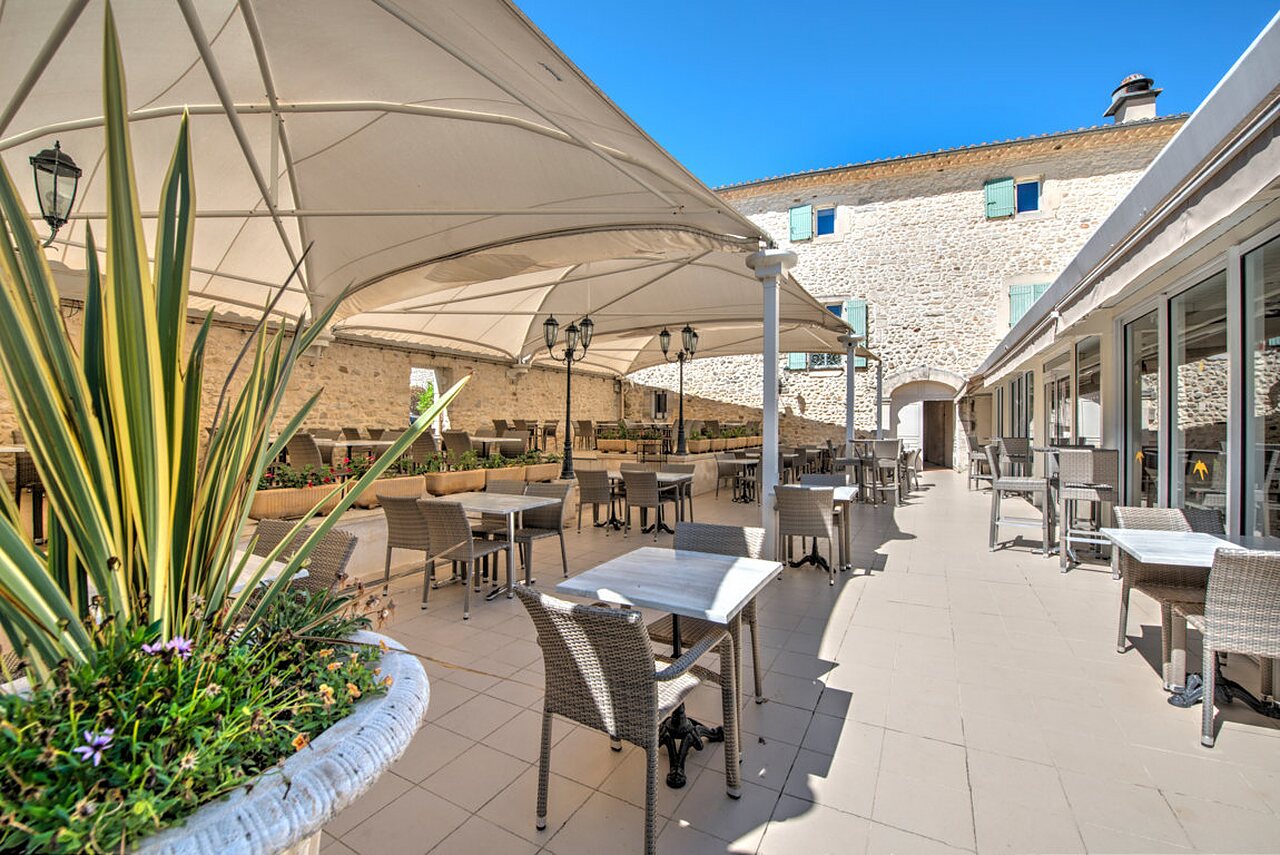 Terraza sombreada de restaurante y bar, mesas, en camping CLICOCHIC Ch�teau de Boisson (30).