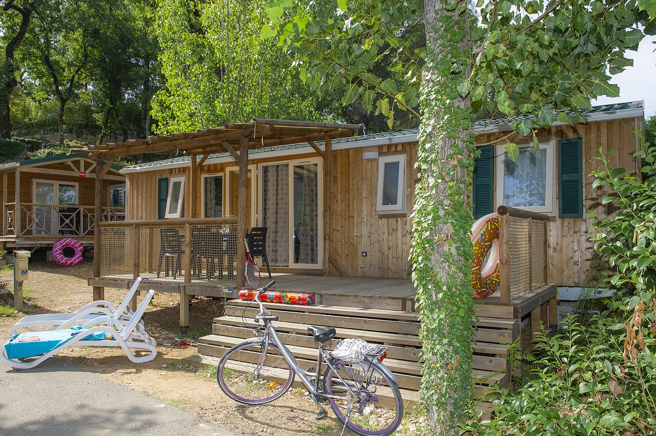 Mobil-home de madera con terraza y bicicleta en el camping CLICOCHIC Ch�teau de Boisson en All�gre-les-Fumades (30).