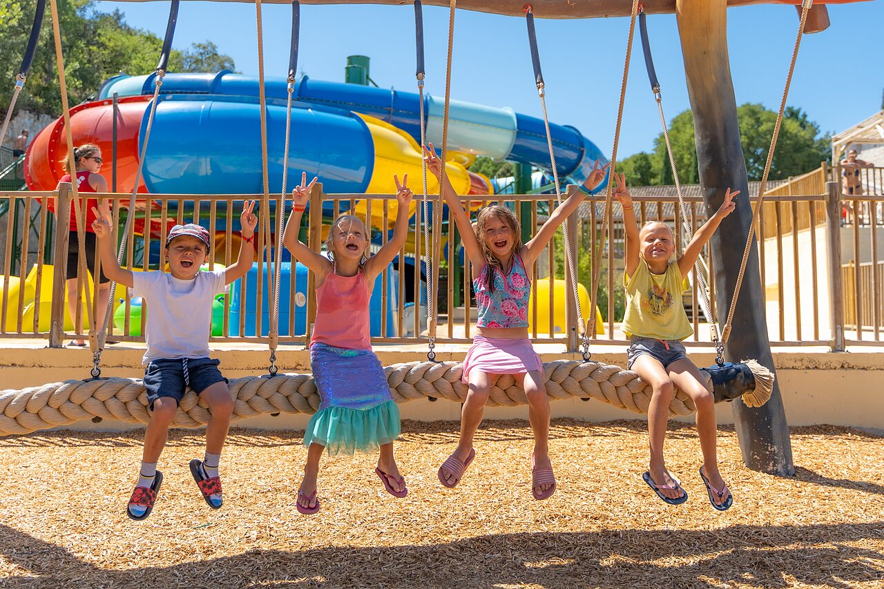 Ni�os sonrientes en columpio, toboganes acu�ticos en camping CLICOCHIC Ch�teau de Boisson (30).