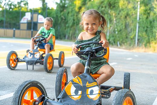 Ni�os sonrientes en karts de pedales en el camping CLICOCHIC Ch�teau de Boisson en All�gre-les-Fumades (30).