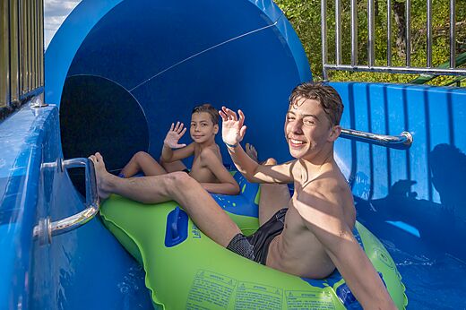 Niños en flotador en tobogán acuático en el camping CLICOCHIC Château de Boisson.