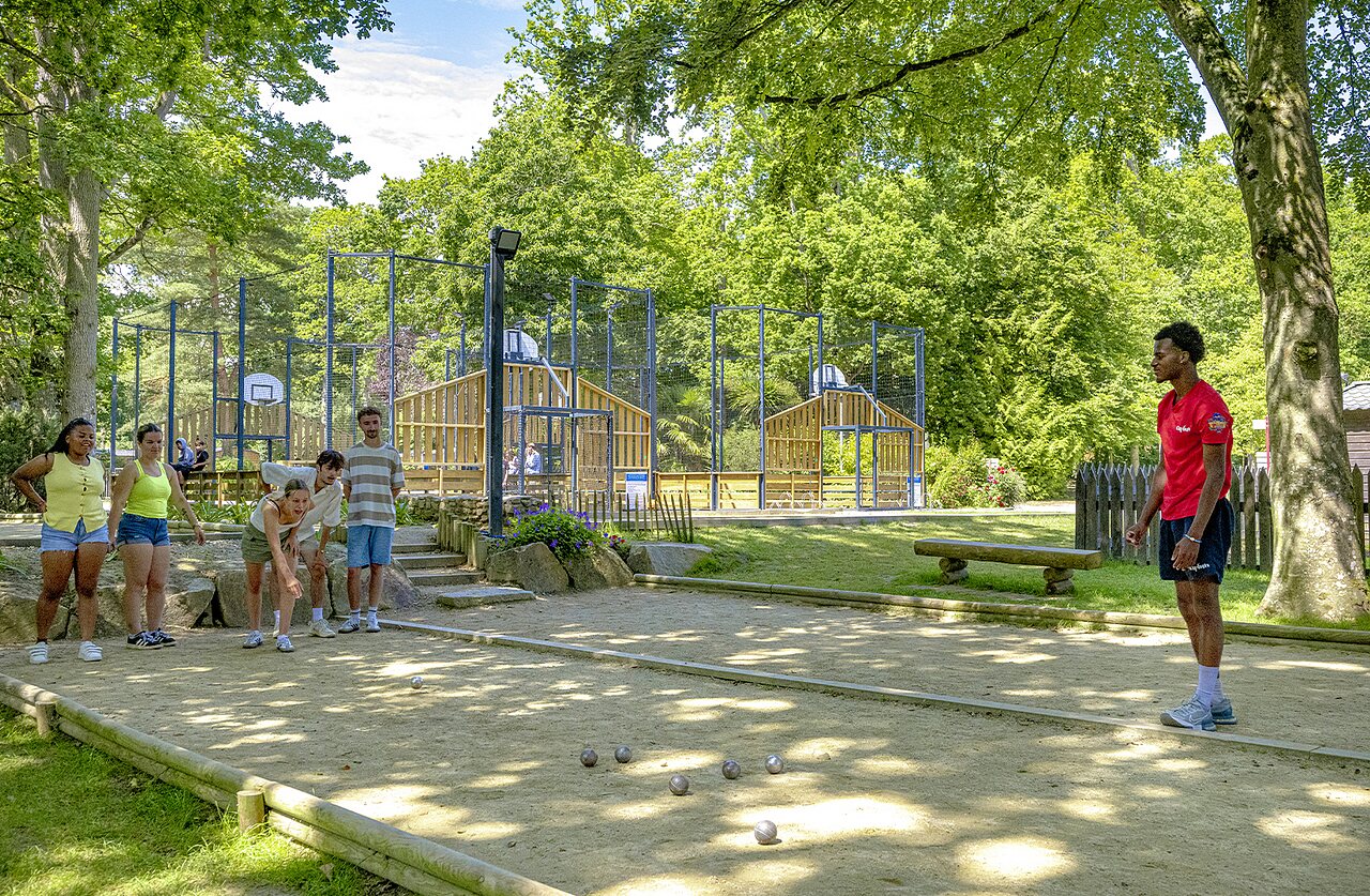 J�venes jugando a la petanca, cancha multideporte de fondo en el camping CAPFUN Ch�teau de Galin�e en SAINT CAST LE GUILDO (22).