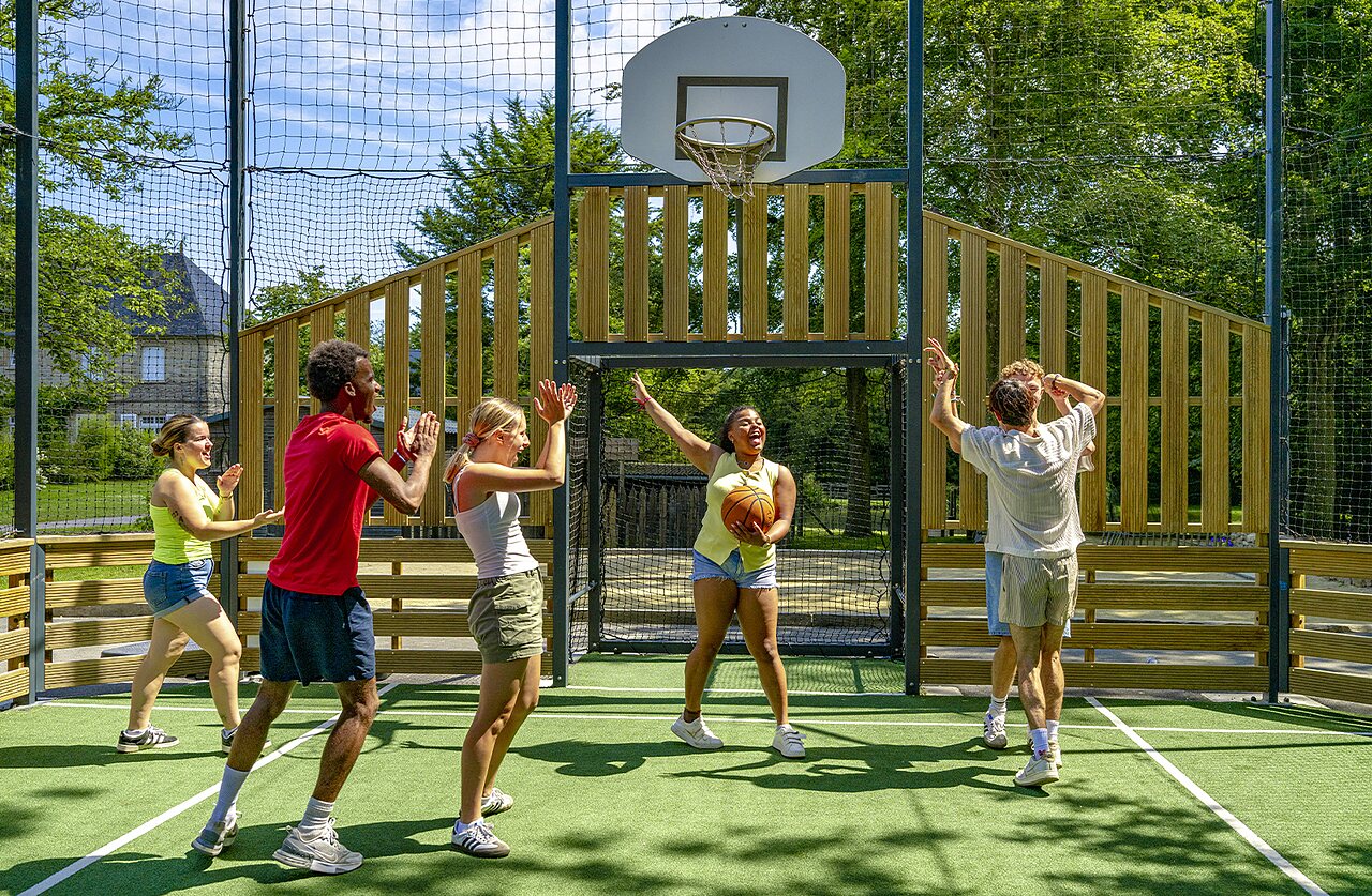 J�venes jugando baloncesto en la cancha multideportiva del camping CAPFUN Ch�teau de Galin�e.