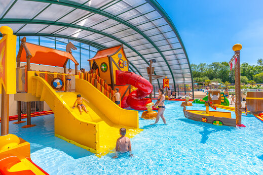 Zona de juegos acuáticos cubierta con toboganes y niños en CAPFUN Chateau d'Arvid en Villerville (14).