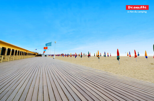 Paseo de Deauville con cabinas de playa y sombrillas coloridas en Normandía.