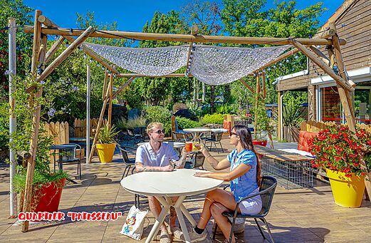 Terraza sombreada de restaurante con pareja en el camping CAPFUN La Chênaie en PORNIC (44).