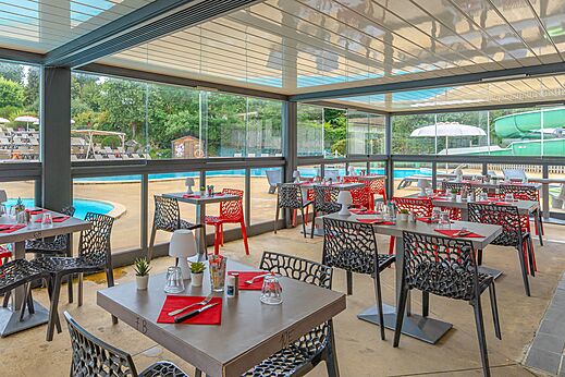 Restaurante moderno con mesas y sillas junto a la piscina en el camping CAPFUN La Ch�naie en PORNIC (44).