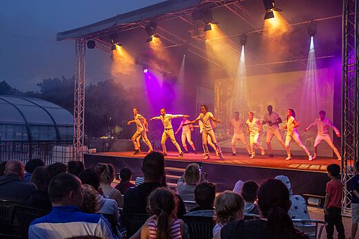 Espectáculo de bailarines en escenario iluminado, público en el camping CAPFUN Chênes en Medis/Royan (17).