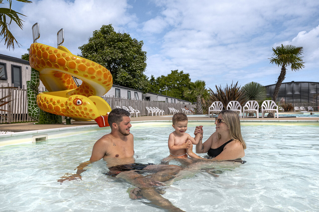 Familia con ni�o disfrutando piscina y tobog�n serpiente en camping CLICOCHIC Chevaliers en HOULGATE (14).