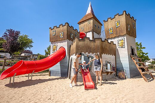 Castillo de juegos con toboganes rojos en el camping CLICOCHIC Chevaliers en HOULGATE (14).
