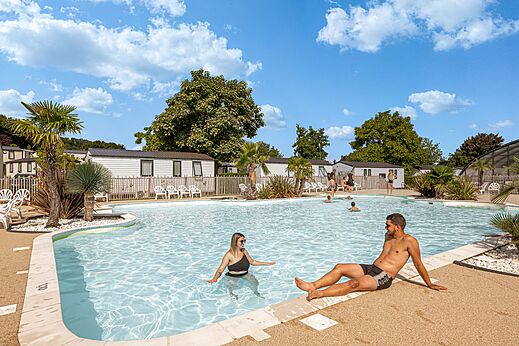 Piscina exterior con bañistas y Mobil-homes en el camping CLICOCHIC Chevaliers en HOULGATE (14).