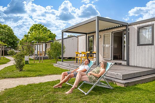 Mobil-home moderno con terraza, pareja relajándose en el camping CLICOCHIC Chevaliers en HOULGATE (14).