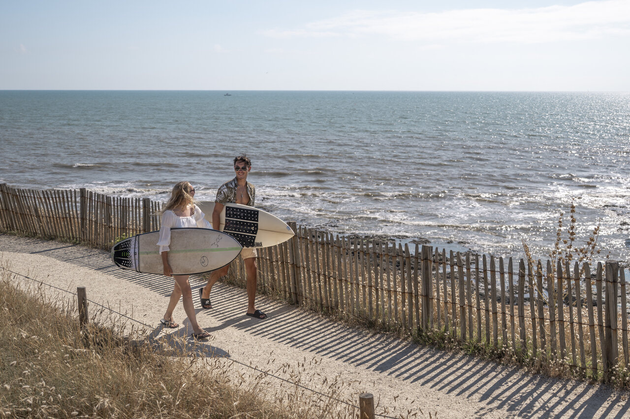 Surfistas con tablas en sendero costero en el camping CLICOCHIC Chouans en Saint Hilaire de Riez.