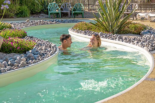 Piscina río lento con pareja sonriente en el camping CLICOCHIC Chouans en SAINT HILAIRE DE RIEZ (85).