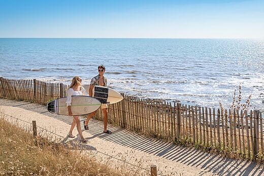 Pareja con tablas de surf en camino al camping CLICOCHIC Chouans en SAINT HILAIRE DE RIEZ (85).