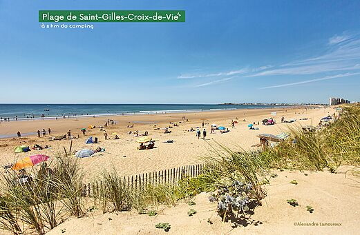 Amplia playa de arena fina en Saint-Gilles-Croix-de-Vie, Vendée, con bañistas y sombrillas.
