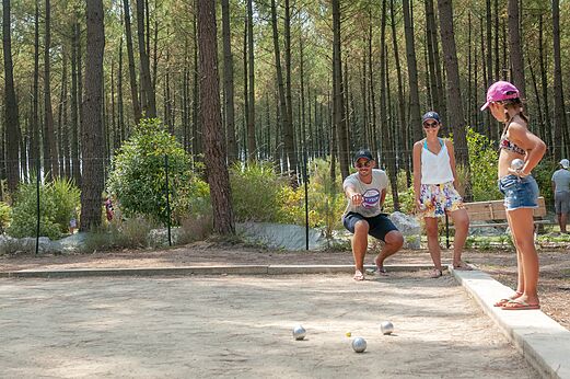 Familia jugando a la petanca en una cancha sombreada en el camping VAGUES OCEANES Les Cigales en Moliets-Plage (40).