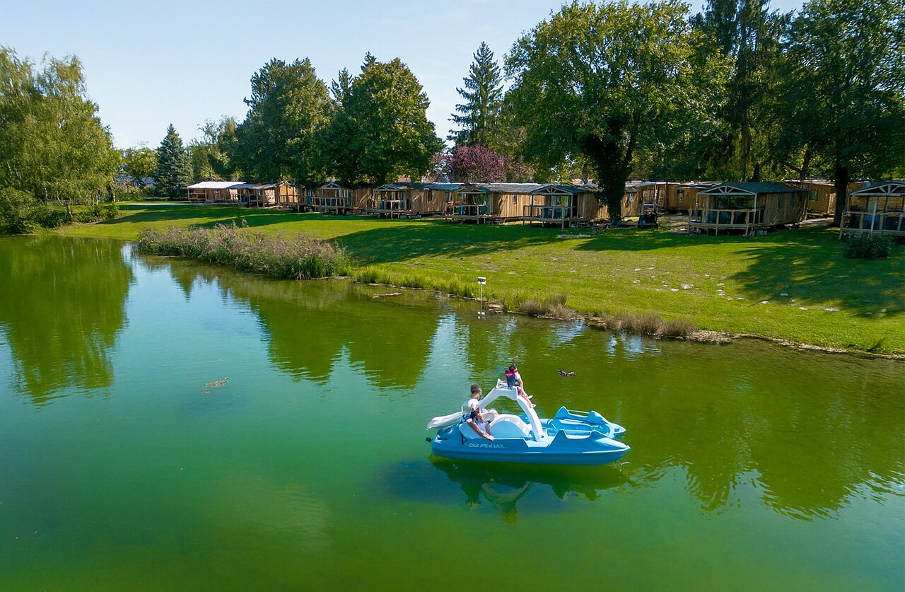 Pat�n a pedales en el lago con alojamientos de madera en el camping CLICOCHIC Au Clair Ruisseau en Gerstheim (67).