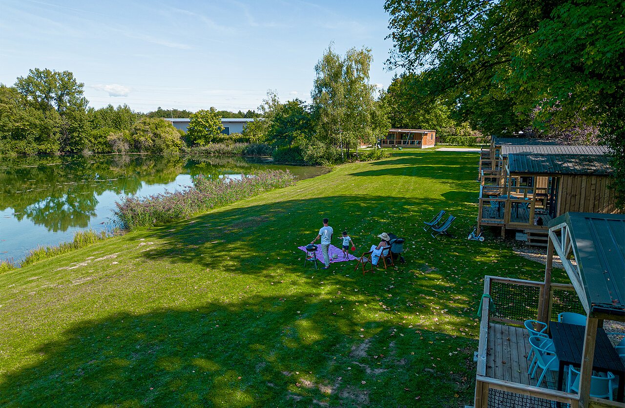 Caba�as de madera, lago y familia de picnic en CLICOCHIC Au Clair Ruisseau.