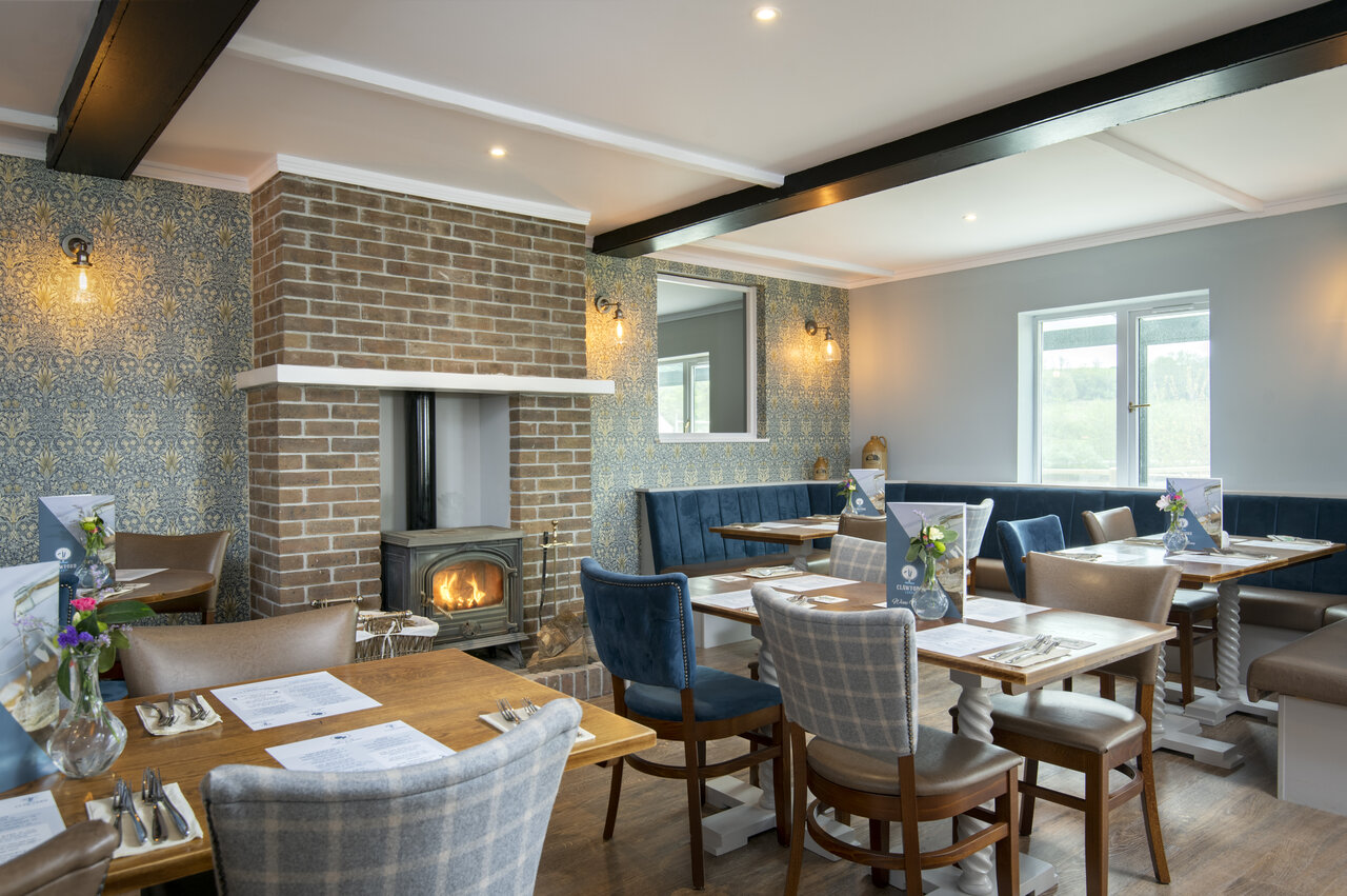 Restaurante interior acogedor, chimenea, mesas en CAPFUN UK Clawford Lakes, Clawton, Holsworthy.