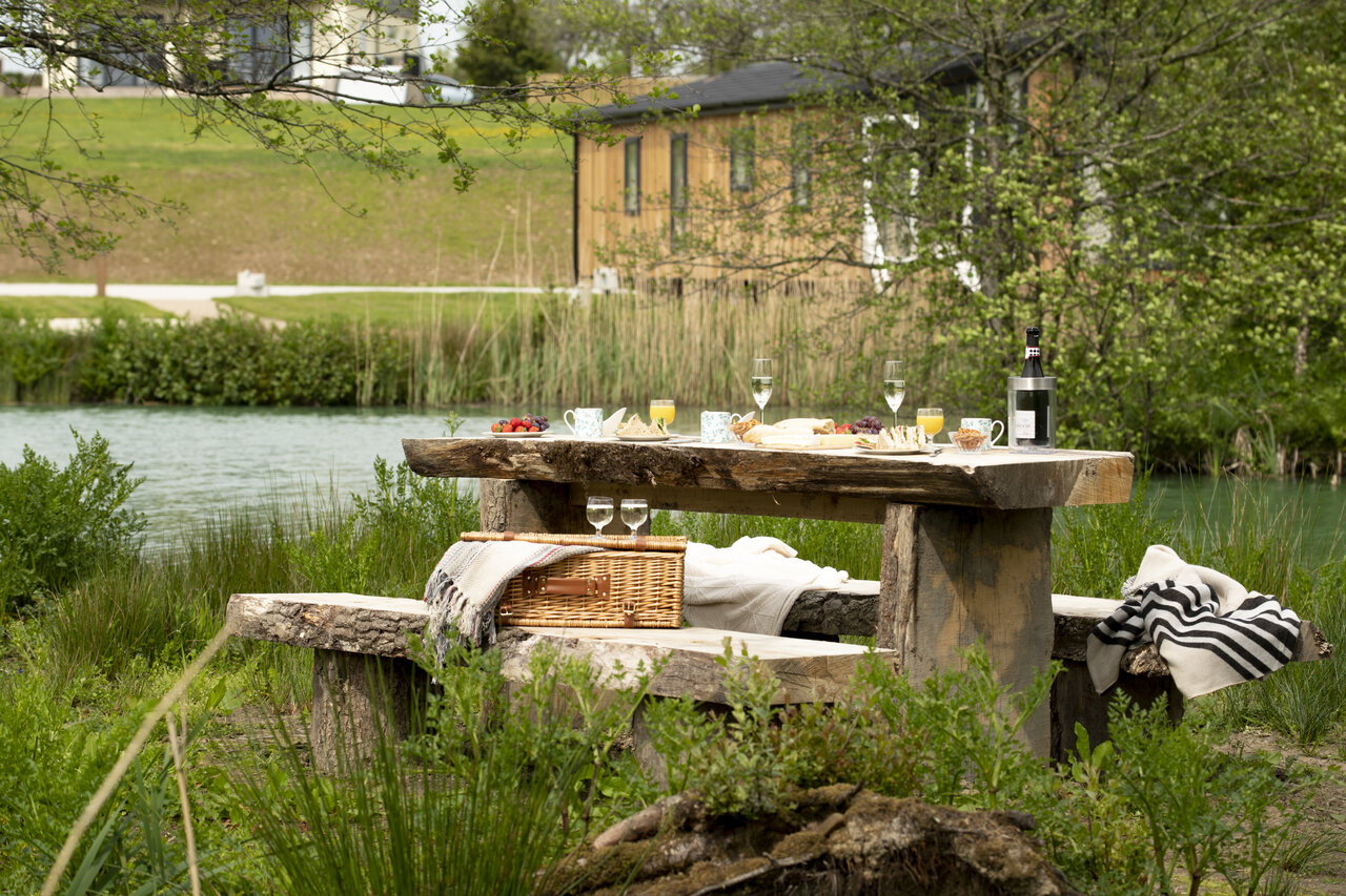 Picnic en mesa de madera, lago, en el camping CAPFUN UK Clawford Lakes.
