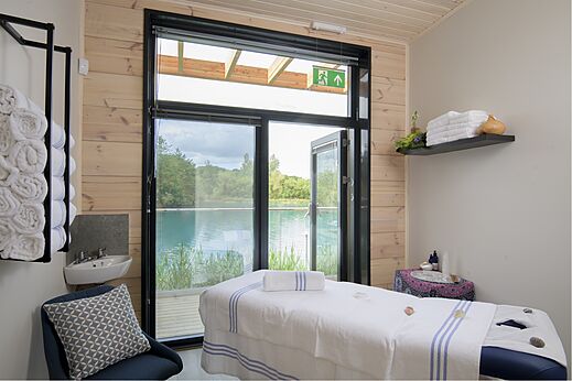 Mesa de masaje en sala de spa con vista al lago en el camping CAPFUN UK Clawford Lakes en Clawton, Holsworthy.