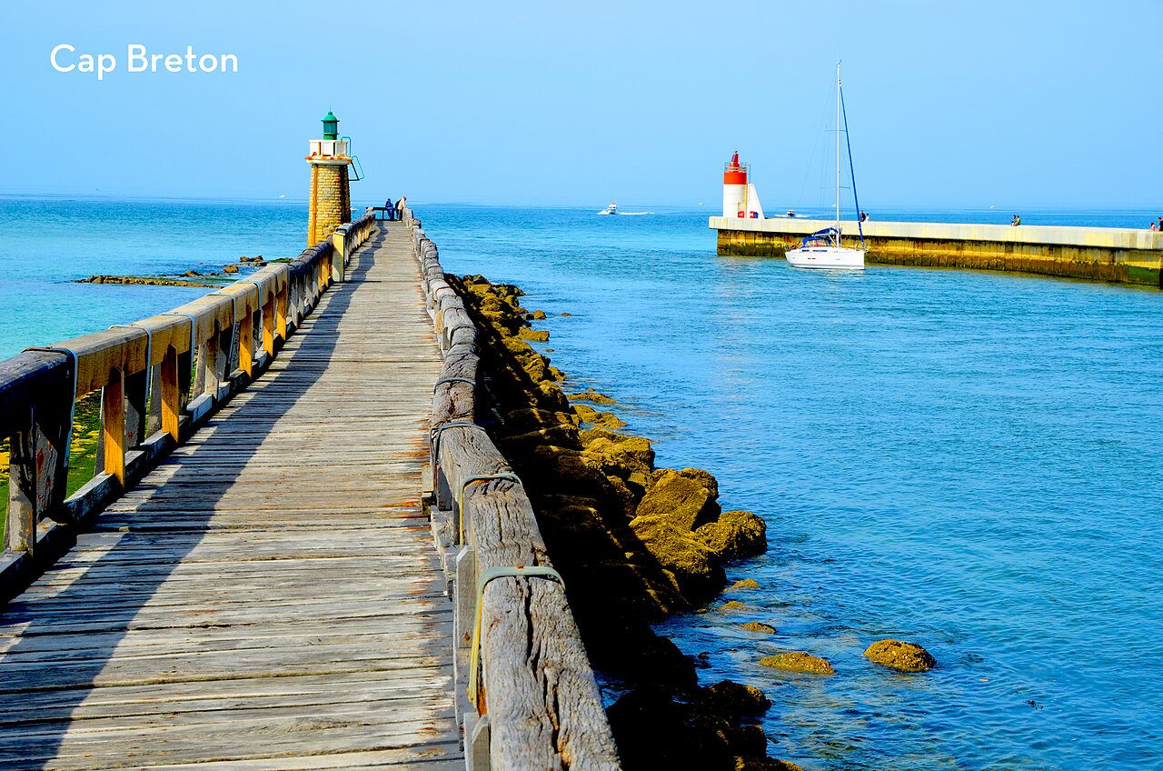 Largo muelle de madera, faros y velero en Capbreton, Landas, para visitar.