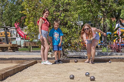 Familia jugando a la petanca en la cancha de juegos del camping CAPFUN Clown Océan en TOSSE (40).