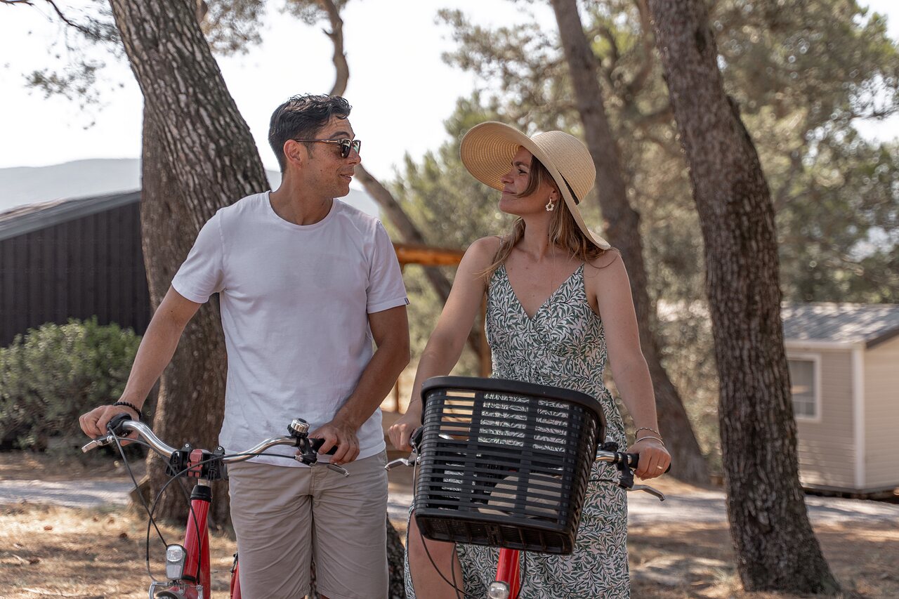 Pareja sonriente con bicicletas en la naturaleza en camping CLICOCHIC Commanderie Rustiques (11).