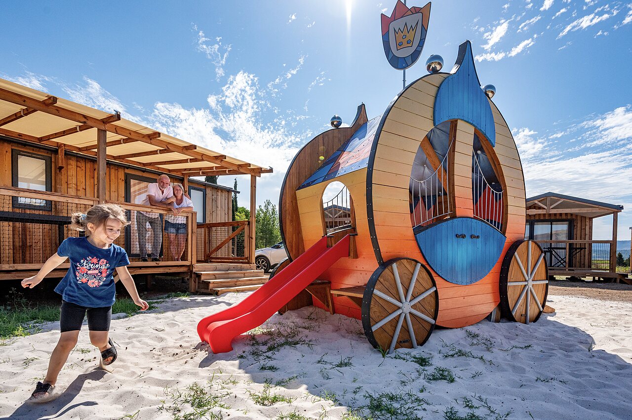 Estructura de juegos en forma de carruaje, tobog�n y alojamientos en el camping CLICOCHIC Commanderie en Rustiques (11).