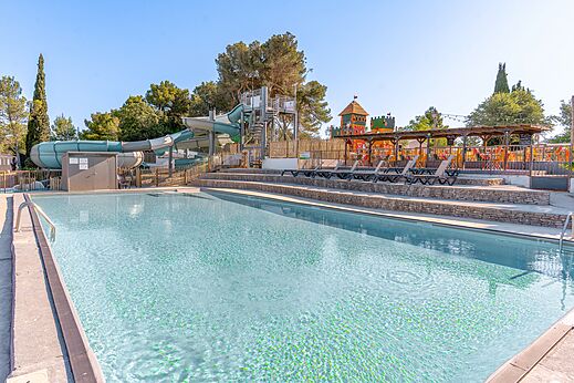 Gran piscina exterior con toboganes y zona de juegos en el camping CLICOCHIC Commanderie en Rustiques (11).