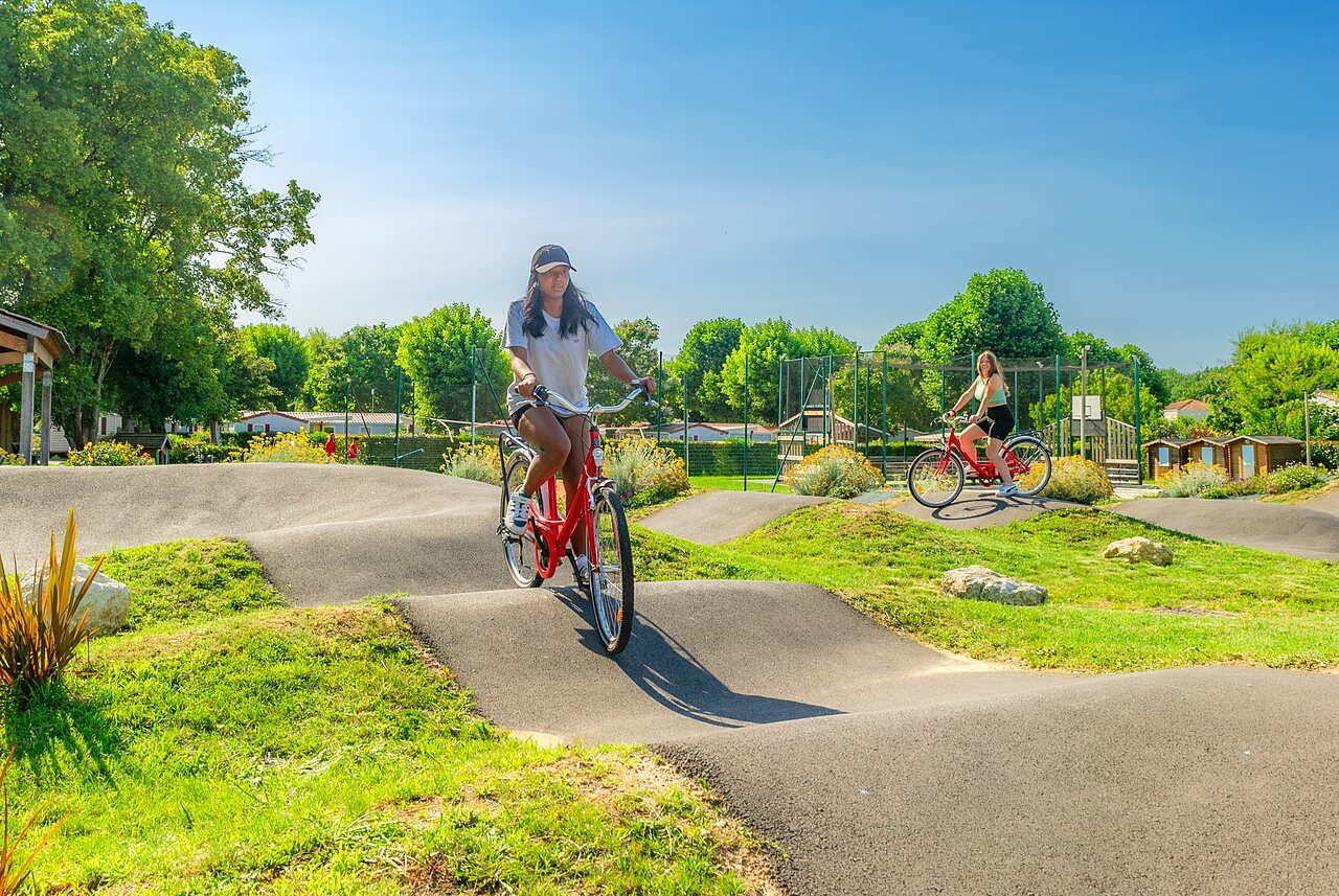 Pista pump track con mujeres en bicicleta en el camping CAPFUN Coquelicots en Royan (17).