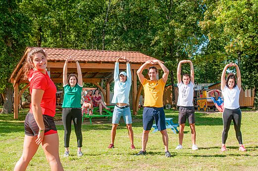 Grupo de adultos estirando al aire libre en el camping CAPFUN Coquelicots en Royan (17).
