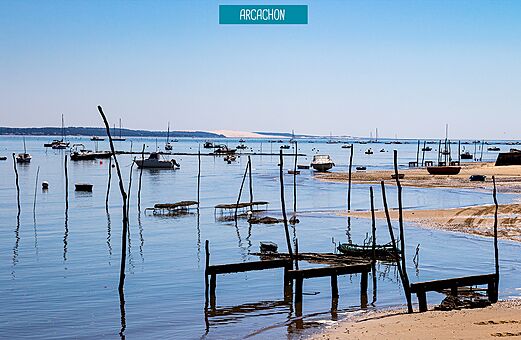 Bahía de Arcachon con barcos y la Duna de Pilat al fondo.
