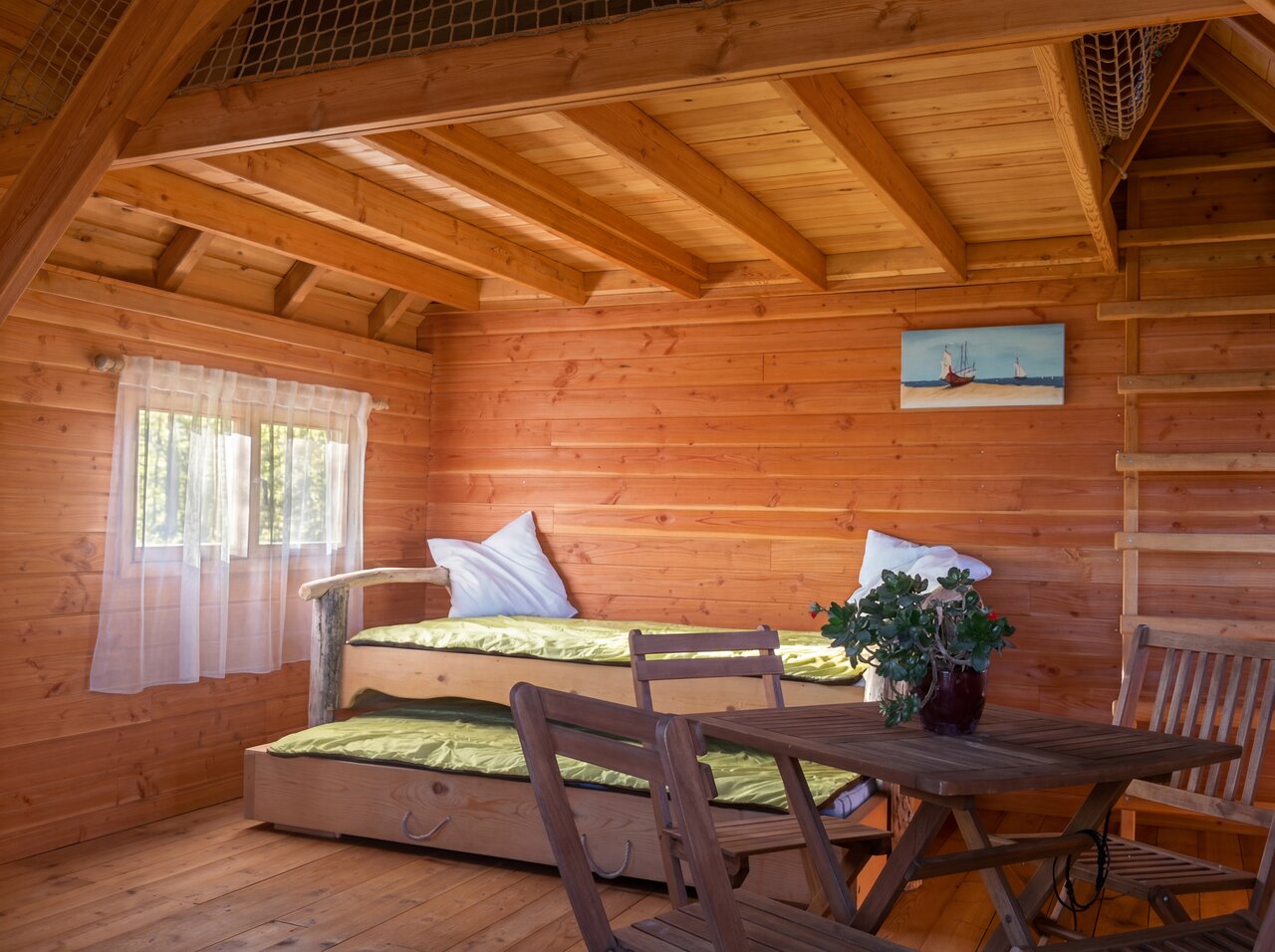 Interior de caba�a de madera con camas nido y mesa en el camping CAPFUN C�te Vermeille: Cabane dans les airs en Port La Nouvelle (11).