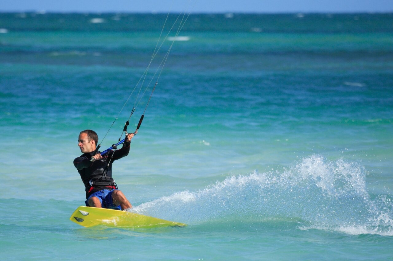 Hombre practicando kitesurf en agua turquesa, salpicaduras din�micas en el camping CAPFUN C�te Vermeille : Cabane dans les airs � Port La Nouvelle (11).