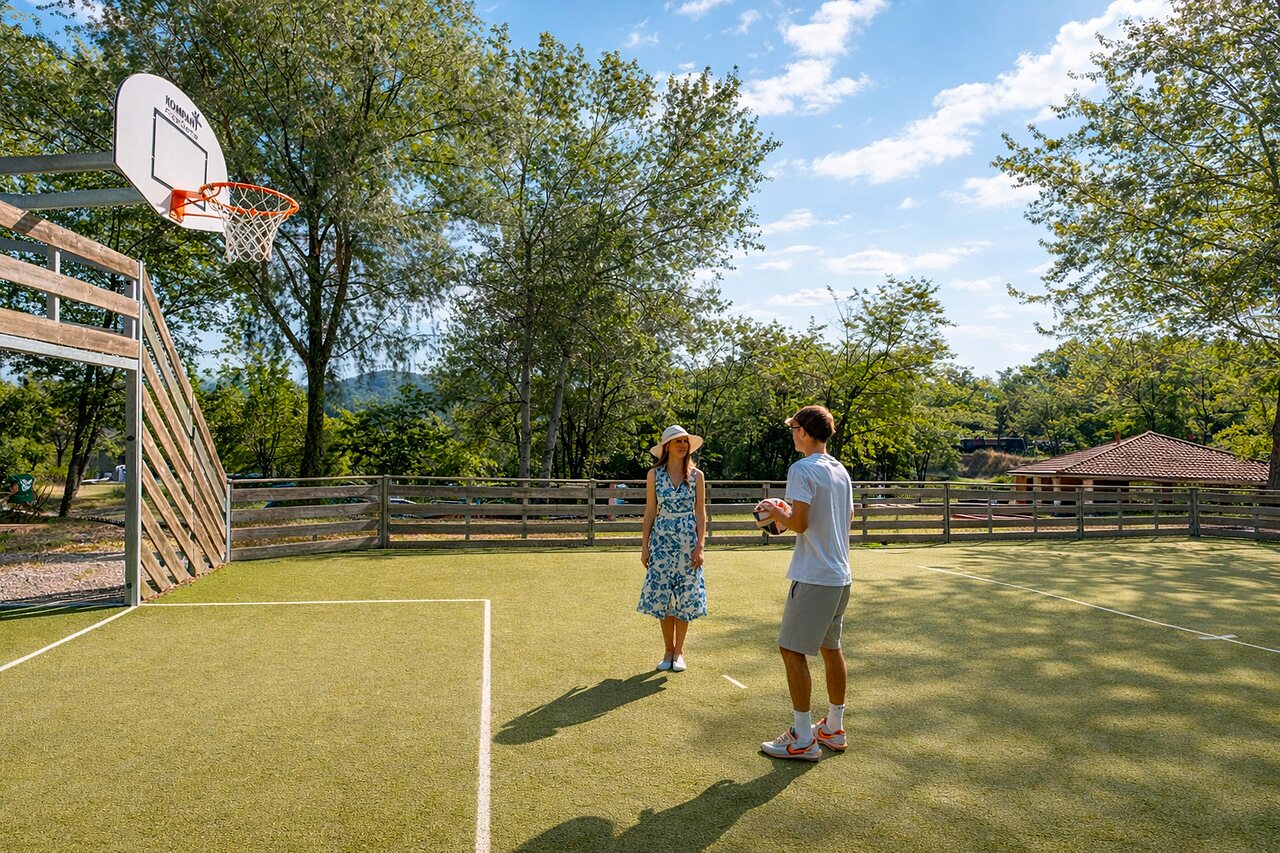 Pista multideporte con canasta de baloncesto y pareja en camping CLICOCHIC Couriou Recoubeau-Jansac (26).