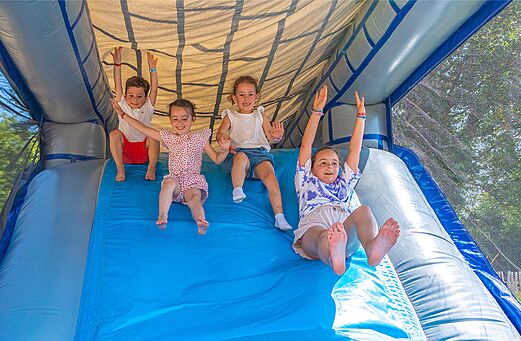 Niños divirtiéndose en un tobogán hinchable en el camping CLICOCHIC Couriou en Recoubeau-Jansac.