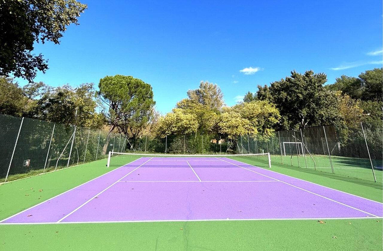 Cancha de tenis morada y verde en el camping CLICOCHIC Couteli�re en Lagnes (84).