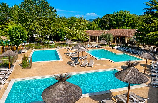 Piscinas exteriores con sillas y sombrillas en el camping CLICOCHIC Couteli�re en Lagnes (84).
