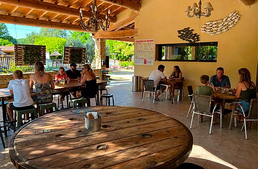 Zona de restaurante y bar cubierta con familias en el camping CLICOCHIC Couteli�re (84).