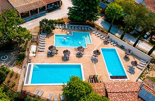 Vista a�rea de varias piscinas con sillas en el camping CLICOCHIC Couteli�re en Lagnes (84).