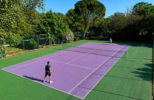 Pista de tenis morada con dos jugadores en el camping CLICOCHIC Couteli�re en Lagnes (84).