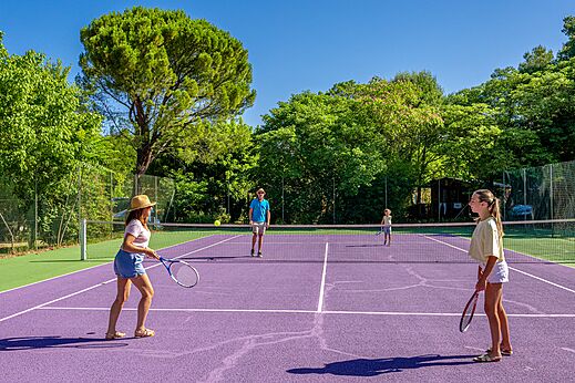 Familia jugando al tenis en cancha morada en el camping CLICOCHIC Coutelière en Lagnes (84).